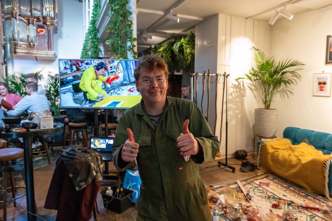 Ward Schepman giving two thumbs up during live painting, with the audience behind him.